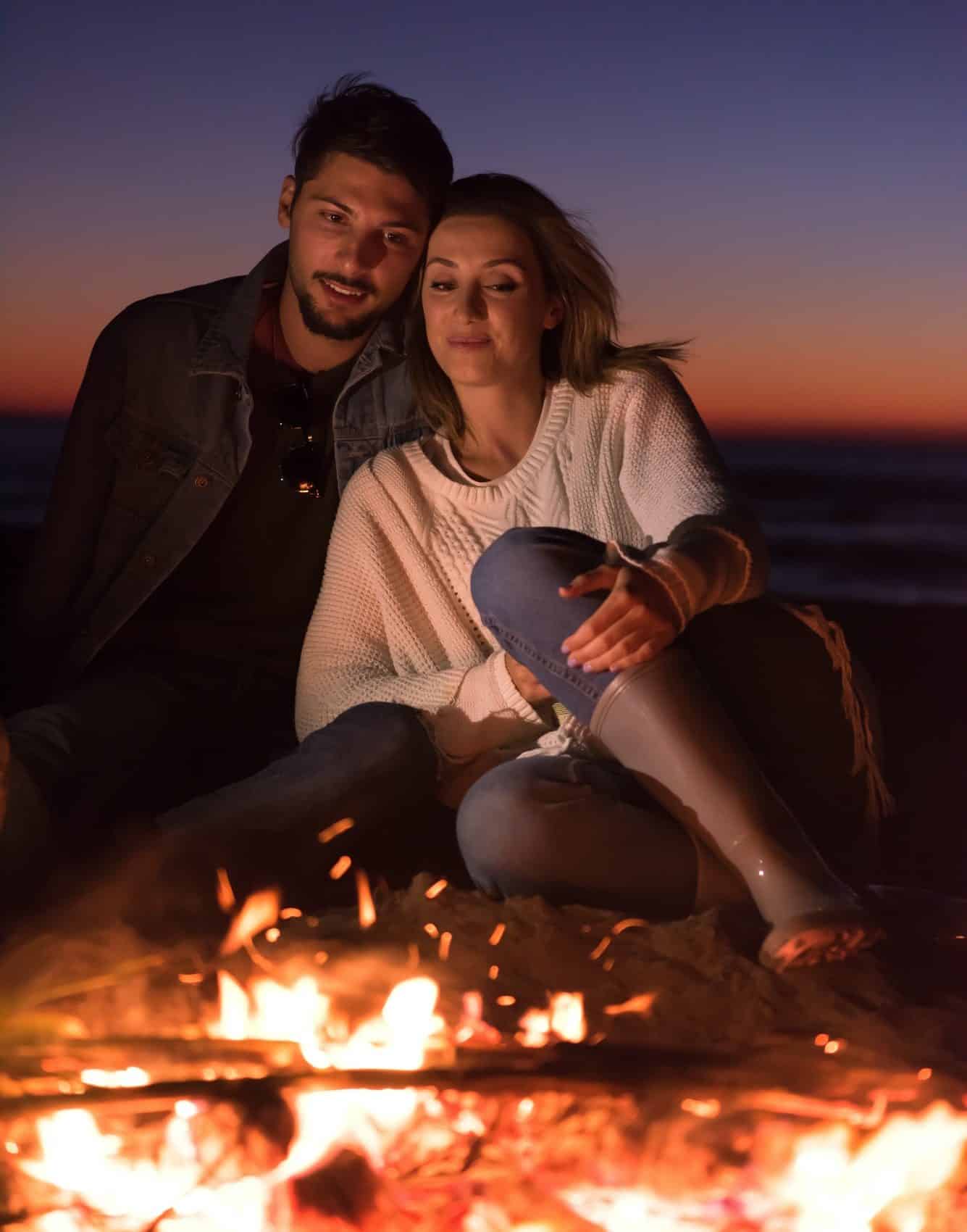 Portrait of young couple enjoying at night on the beach e1631510574684