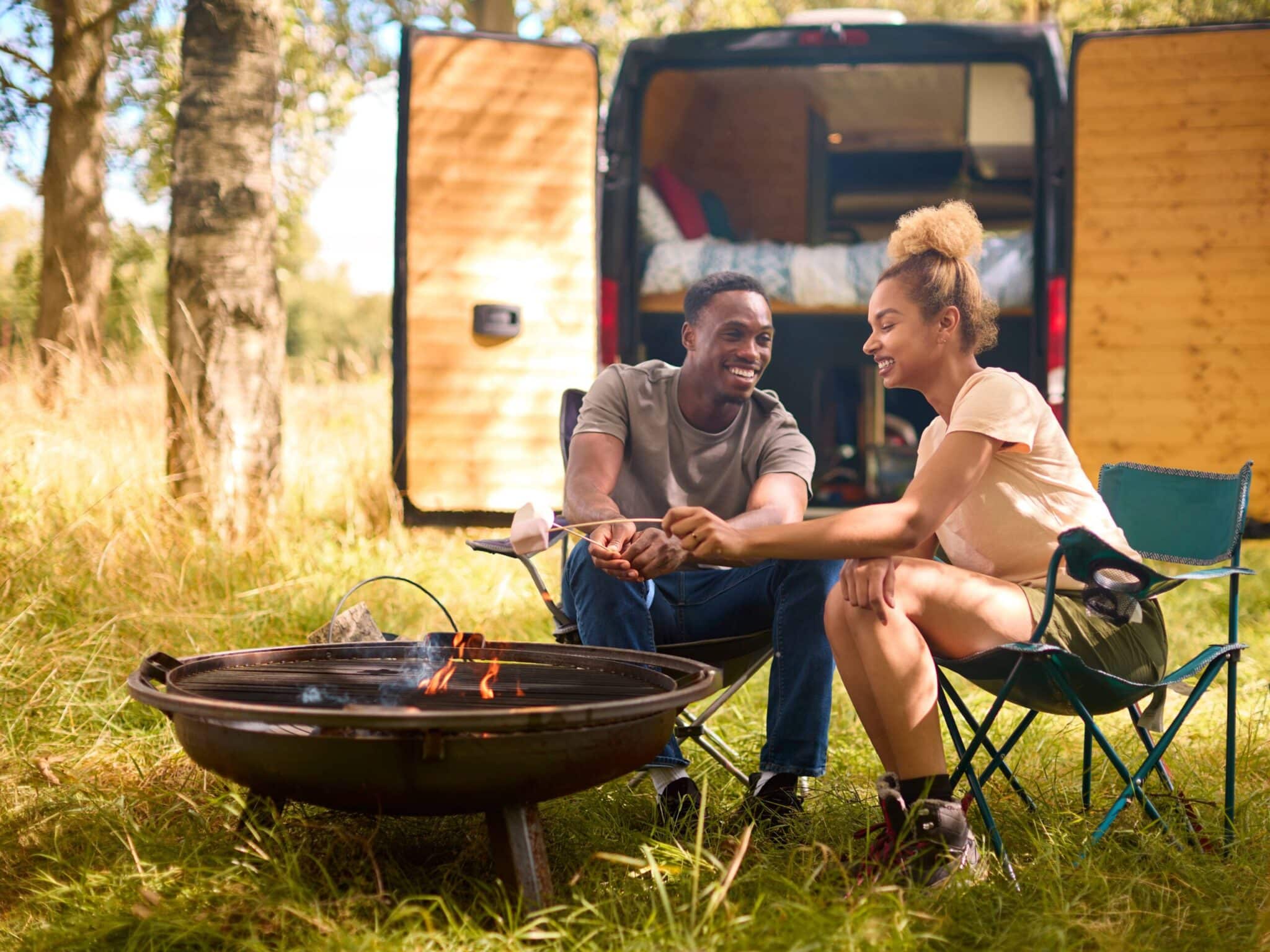 Couple camping in countryside with rv toasting scaled